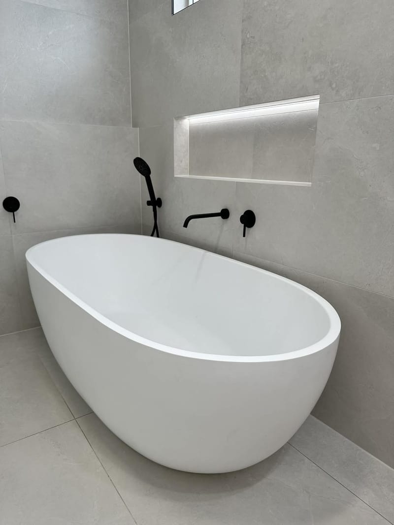 Freestanding bath with matte black tapware and lit wall niche, ASP Build & Co bathroom