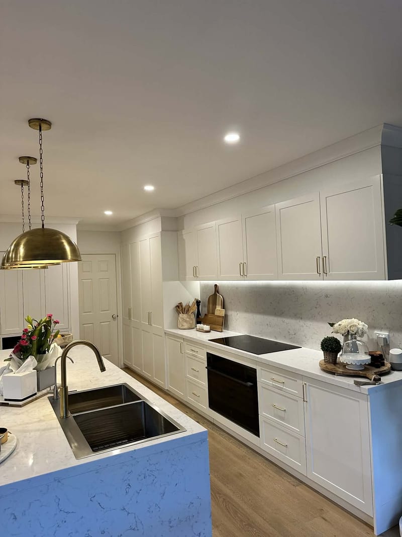 Renovated kitchen with stone island and pendant lights by ASP Build & Co