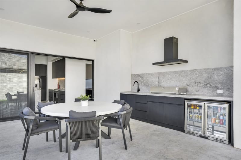 Alfresco outdoor kitchen with built-in barbecue and stone splashback at a Riverlea Park home built by ASP Build & Co