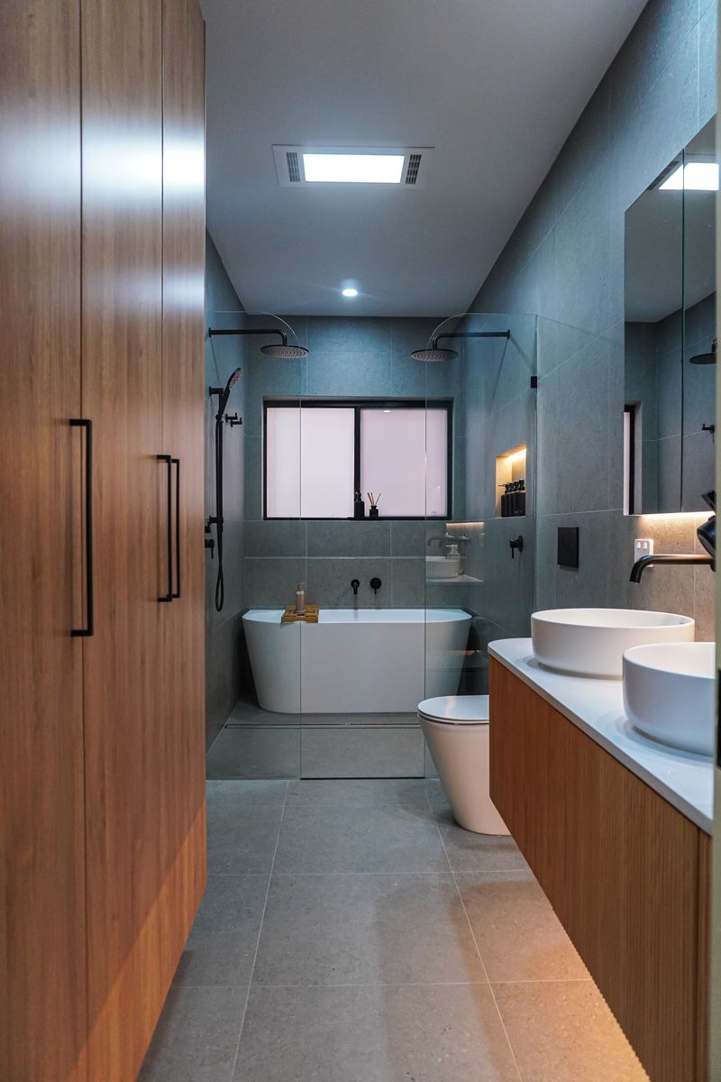 Kingswood main bathroom renovation with floor-to-ceiling timber cabinetry and bath under the window