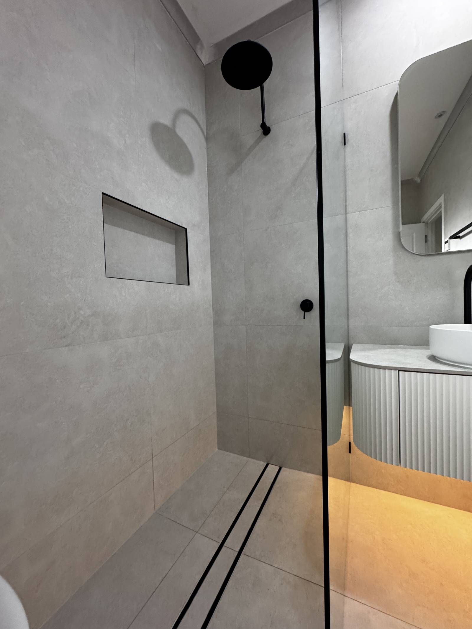 Frameless shower panel, tiled niche and linear floor drain in a renovated Magill bathroom