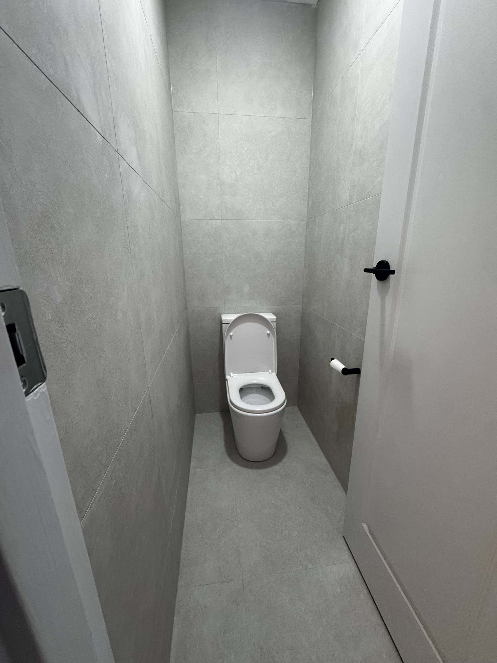 Separate toilet in Magill retiled floor to ceiling with a new wall-faced toilet