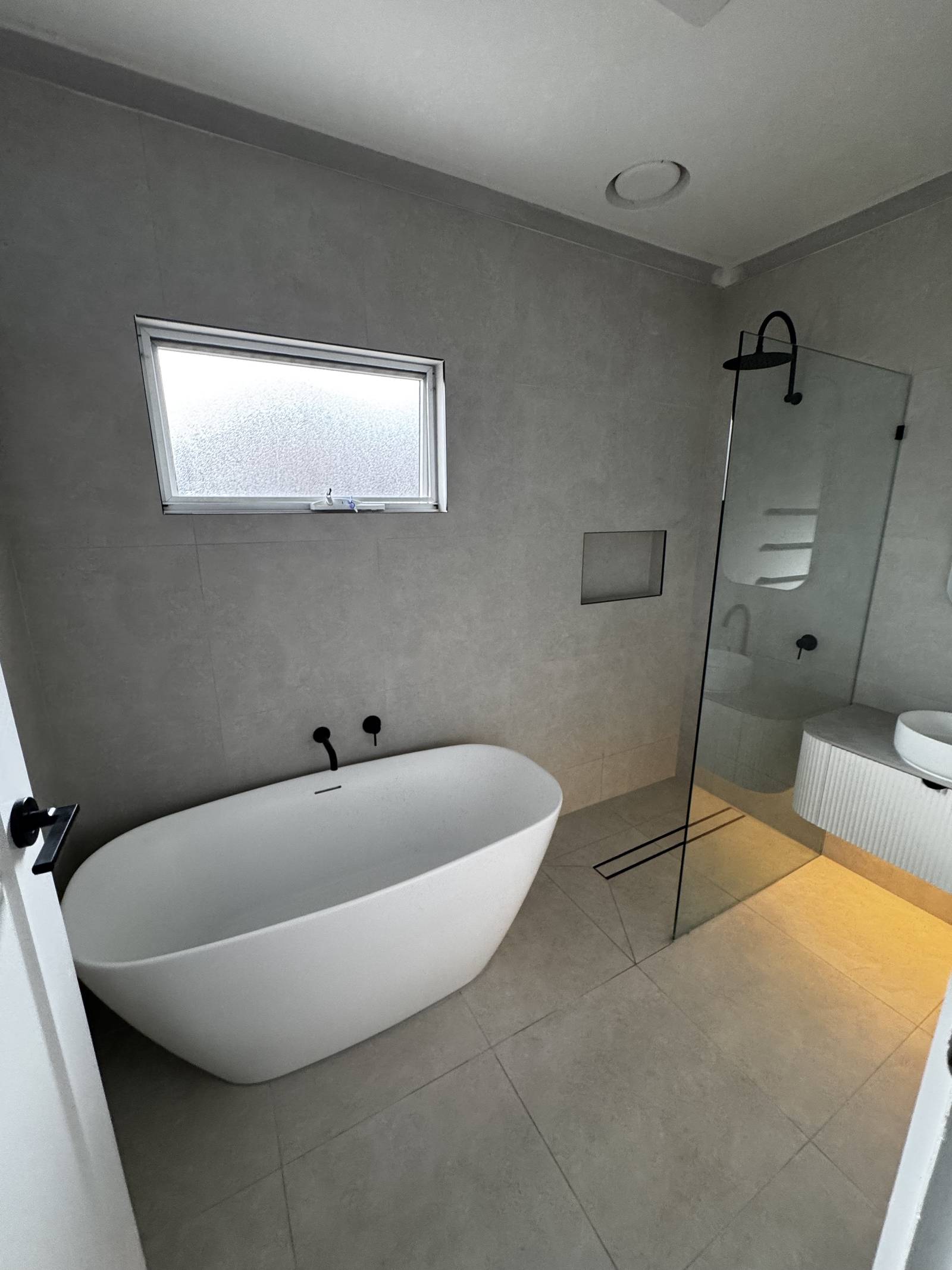 Freestanding bath and black wall mixer seen from the doorway of a renovated Magill bathroom
