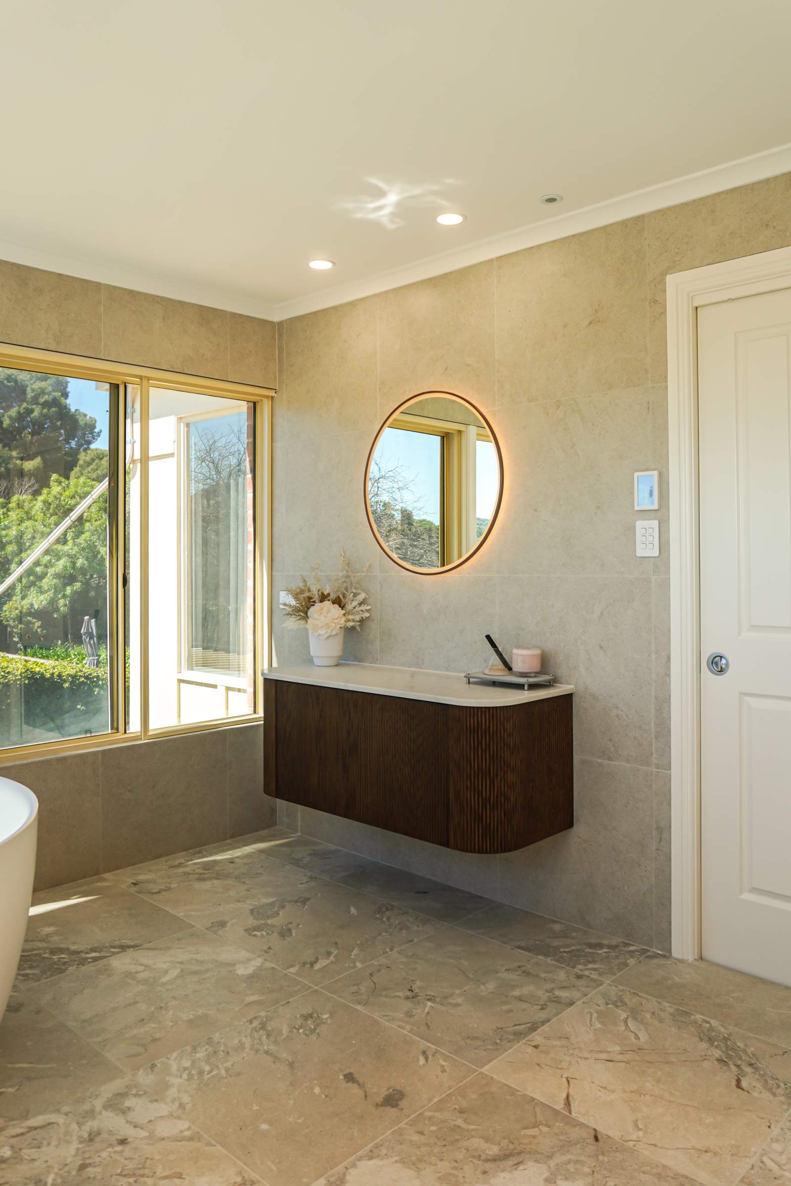 Master ensuite renovation in Torrens Park with round backlit mirror, floating vanity and freestanding bath